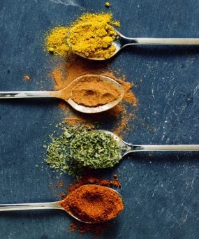 Powdered spices in spoons sitting on a table.