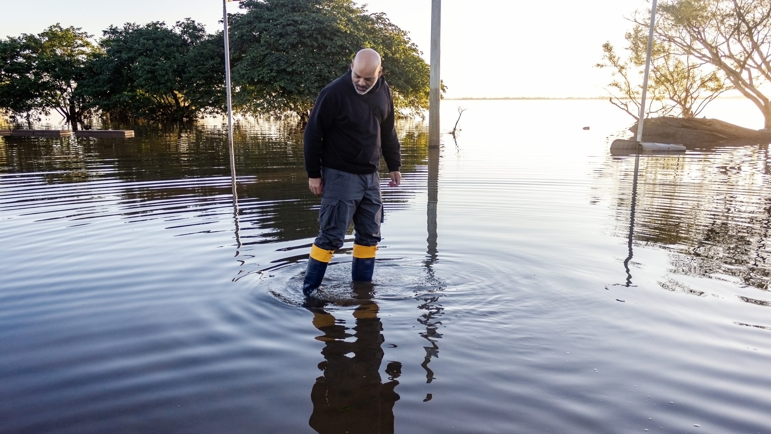 Man wearing boots walks in flood water.