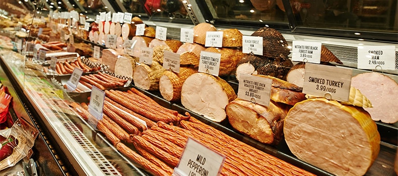 Rows of sliced deli meats in a grocery store setting