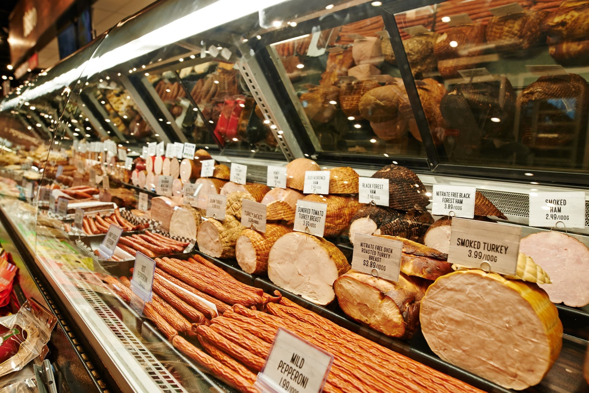 Image of deli meats behind glass at a deli counter.