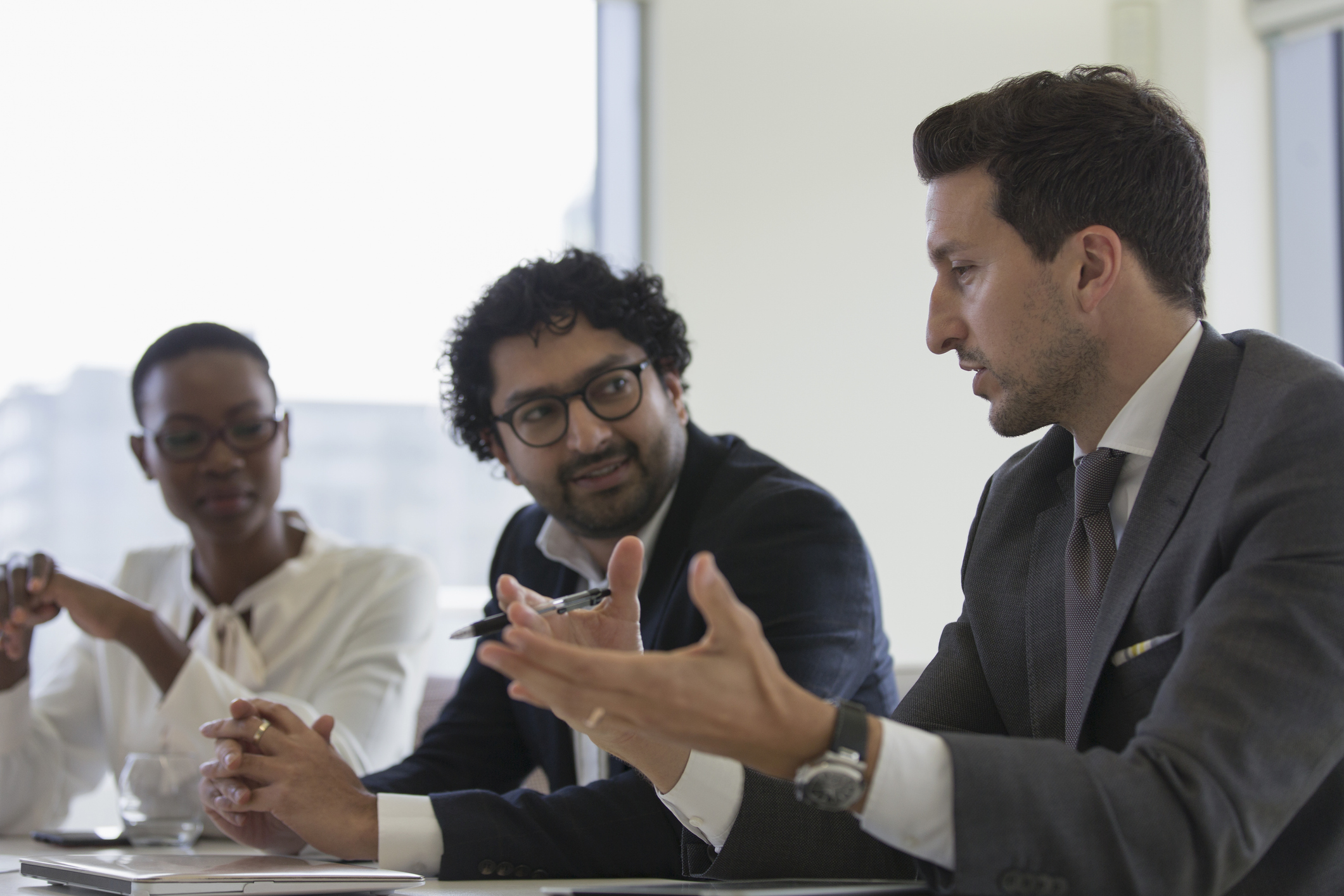 Three people talking at a meeting.
