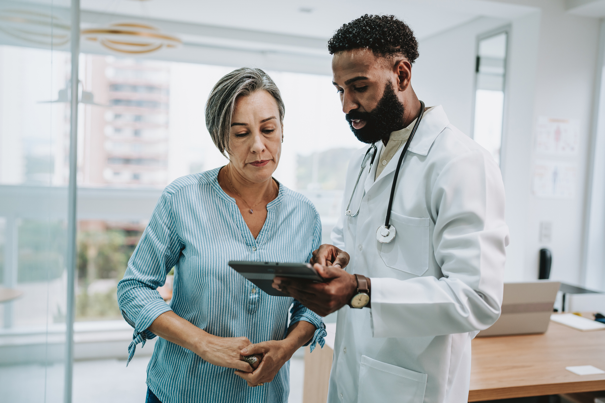 A woman talking to a doctor holding a tablet