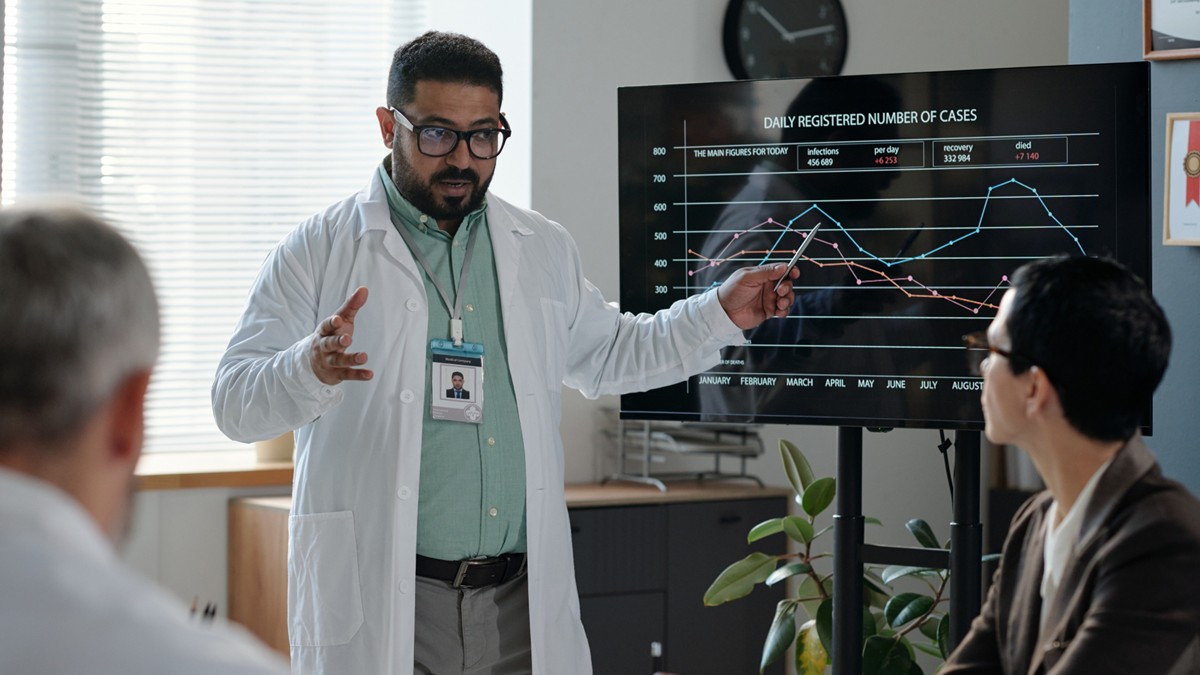 Male HCP presents data at an office conference.