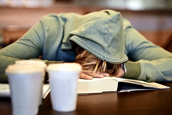 estudiante con la cabeza gacha sobre el escritorio