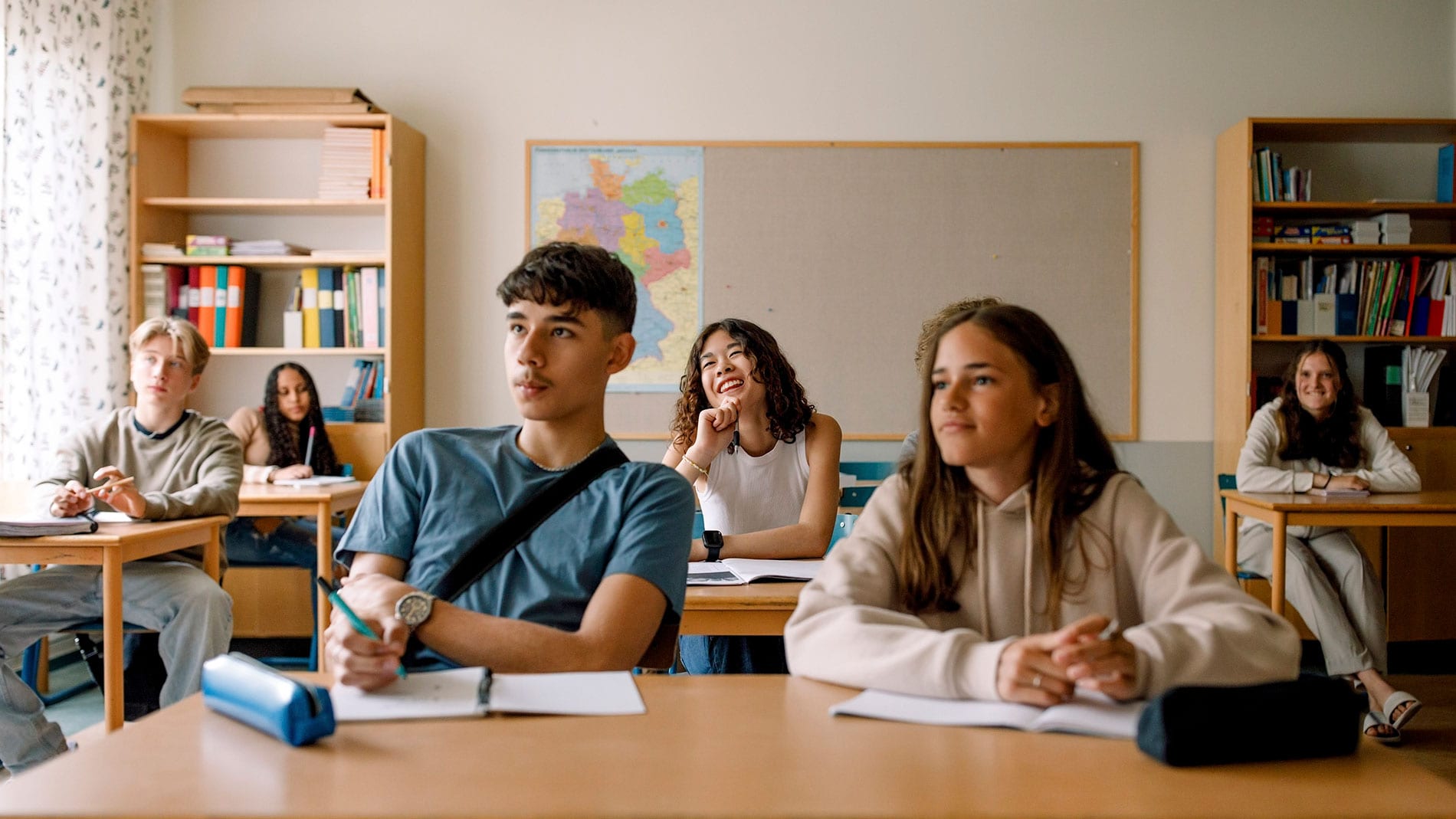 High school students sitting and listening to teacher in the classroom.