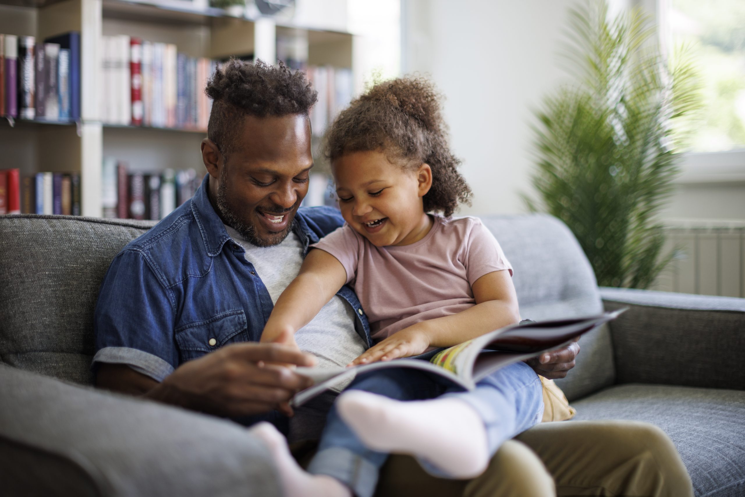 A father and young daughter reading a book.