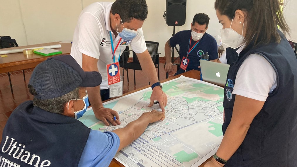Tres funcionarios de salud viendo el mapa de la frontera entre Colombia, Brasil y Perú