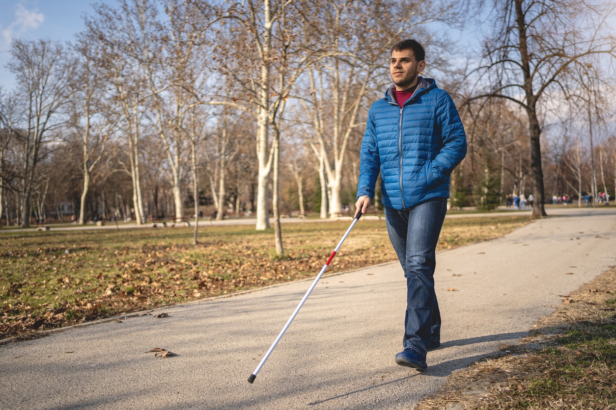 Man walks using a walking cane.