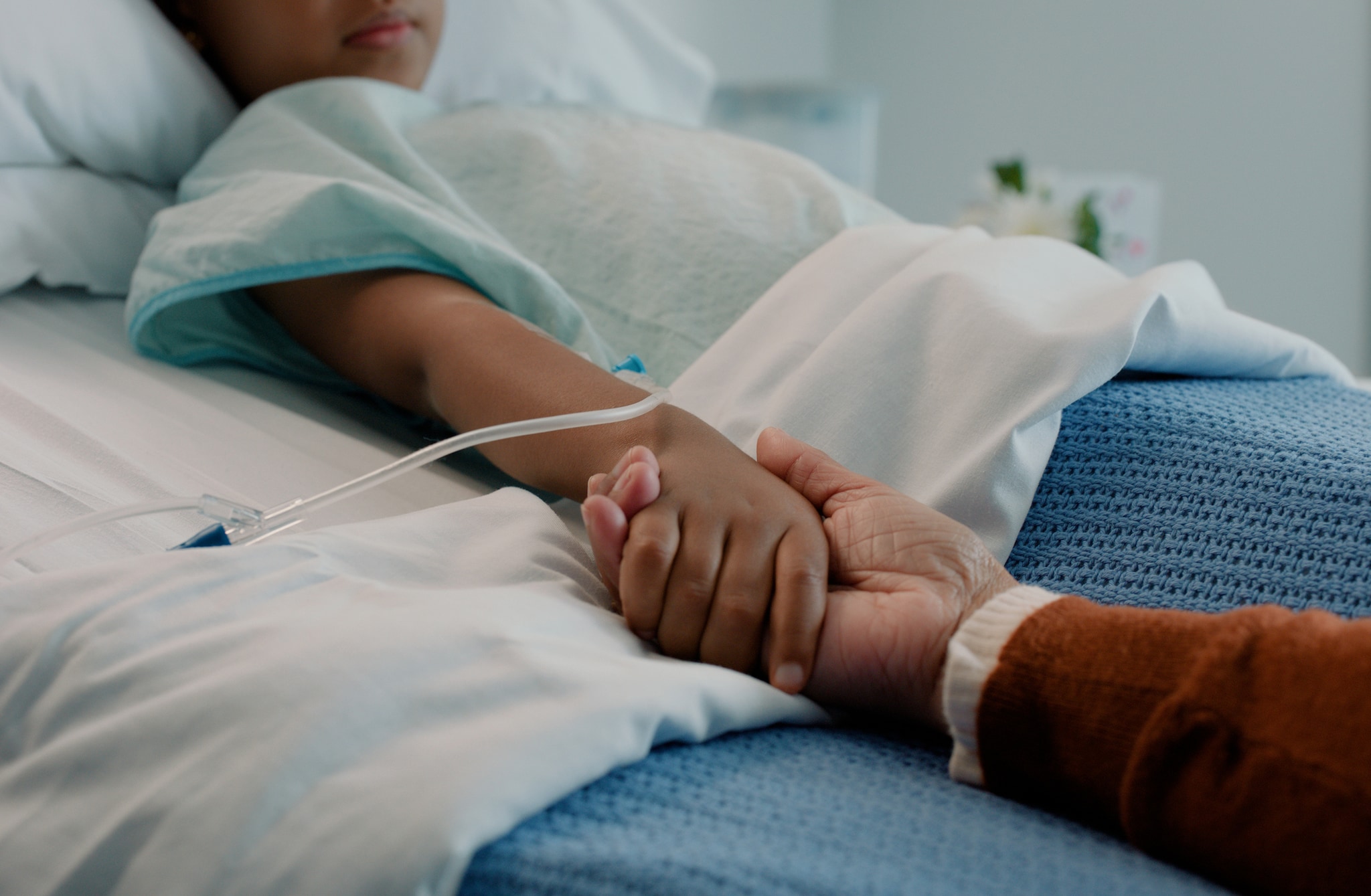 Young patient and caregiver holding hands in a hospital setting