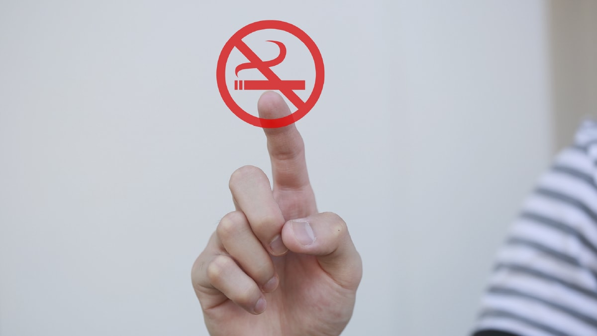 The image shows a hand pointing to a “No Smoking” symbol.