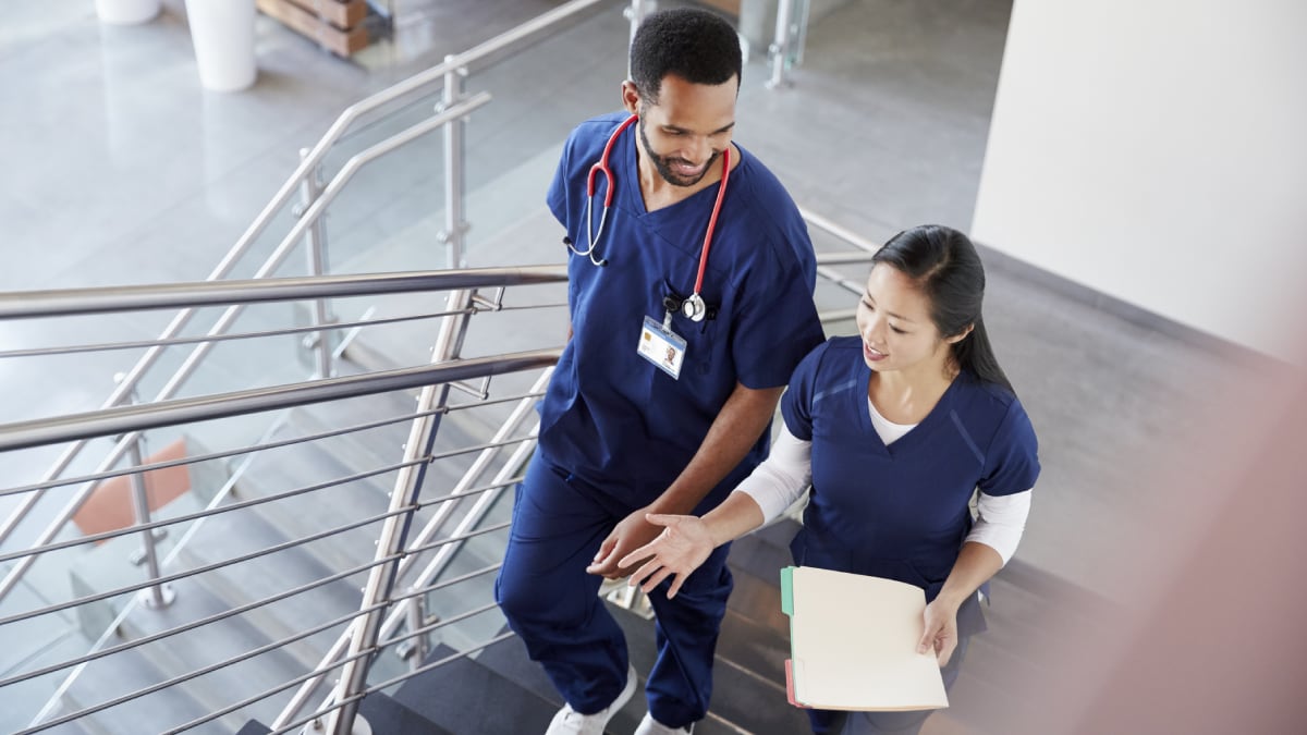 A clinician puts a bandage on another clinician’s arm.