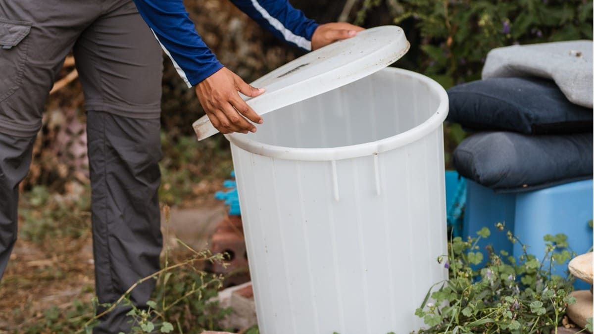 Persona tapando un balde para evitar que los mosquitos pongan huevos en agua estancada.