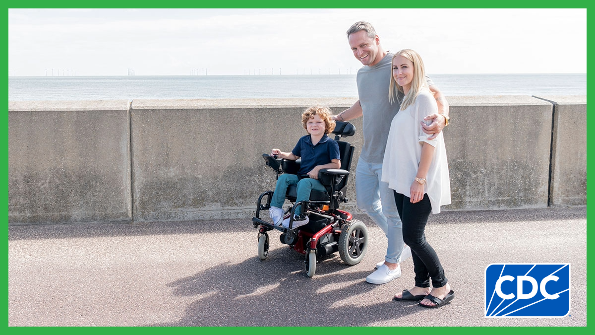 A boy with muscular dystrophy in a powered wheelchair poses with family.