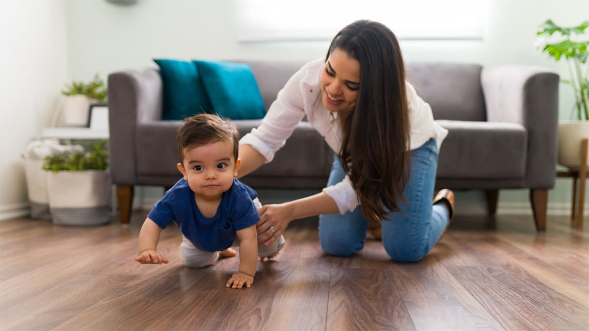 A mom helps her child crawl