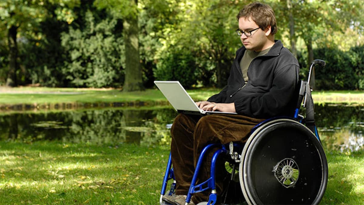 Teen boy in wheelchair looking at laptop