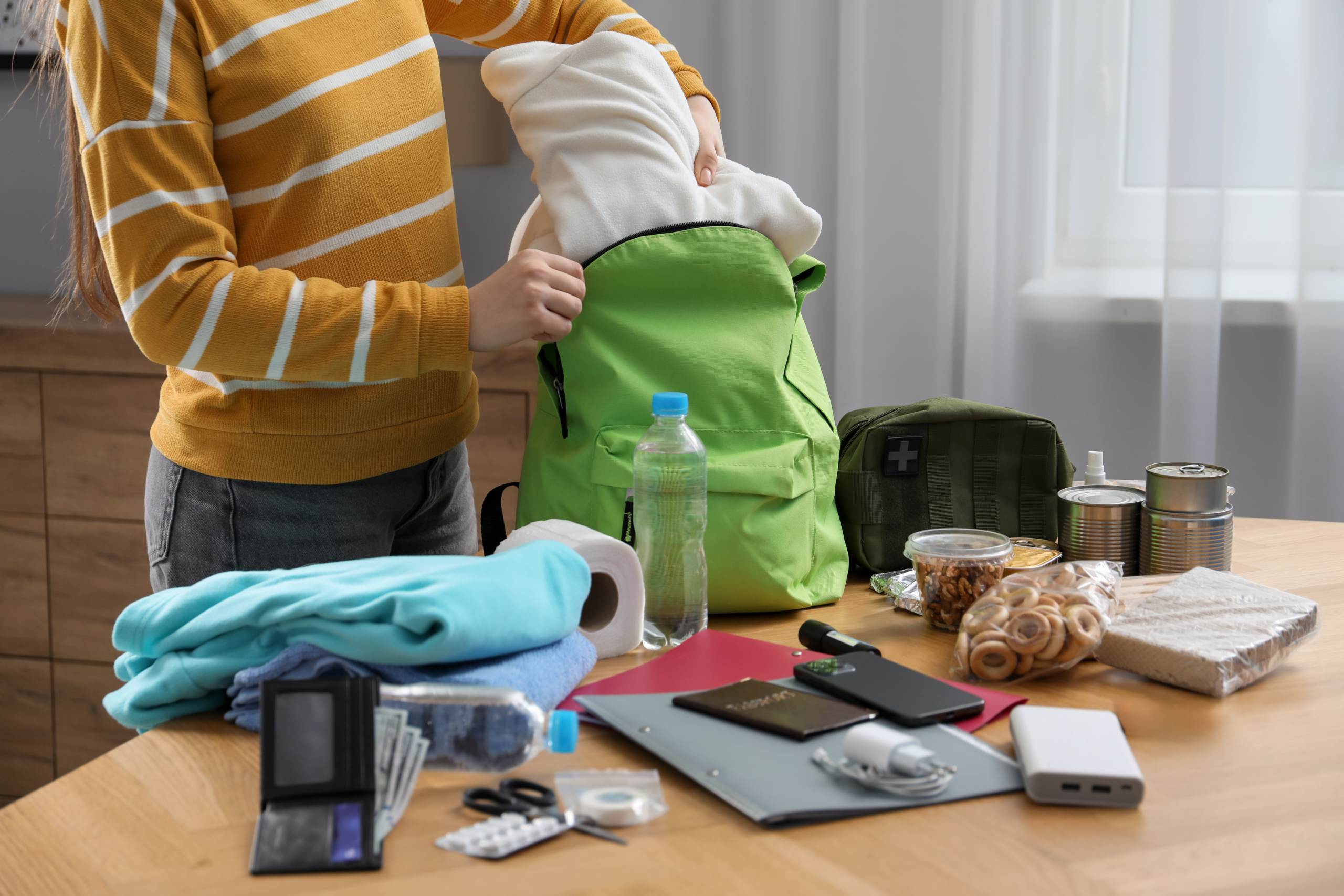 Teen puts emergency kit items into a backpack.