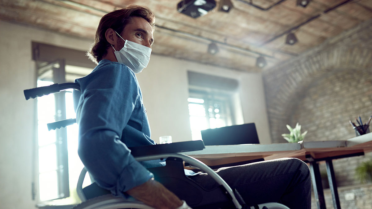 A man in a wheelchair at work wearing a mask