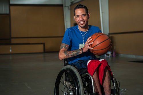 Hombre en silla de ruedas con un bal%26oacute;n de baloncesto en un gimnasio