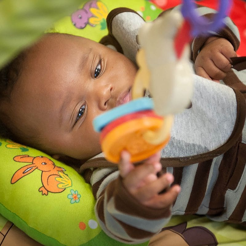 A baby reaches for a hanging toy.