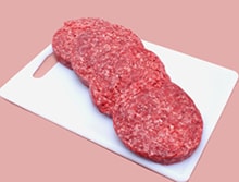 Beef patties on a cutting board.