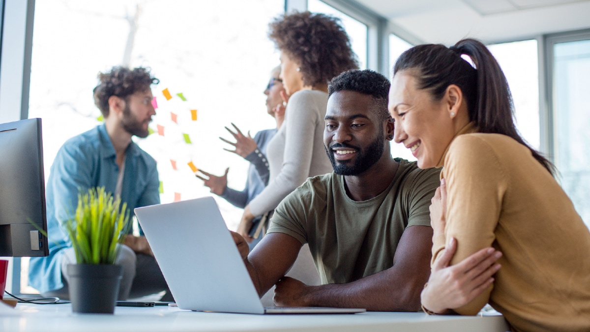 Diverse office workers sitting at laptop computer.