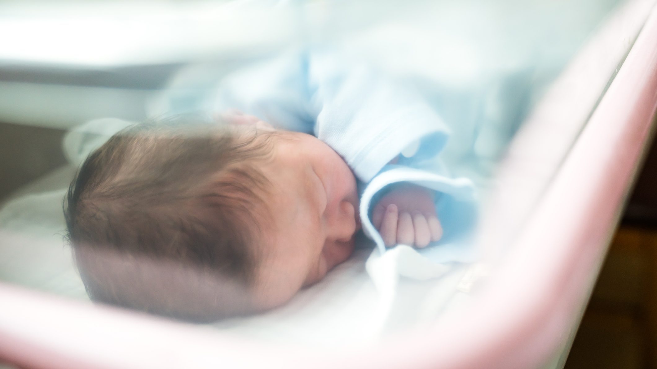 Newborn Baby Sleeping In Hospital Bassinet