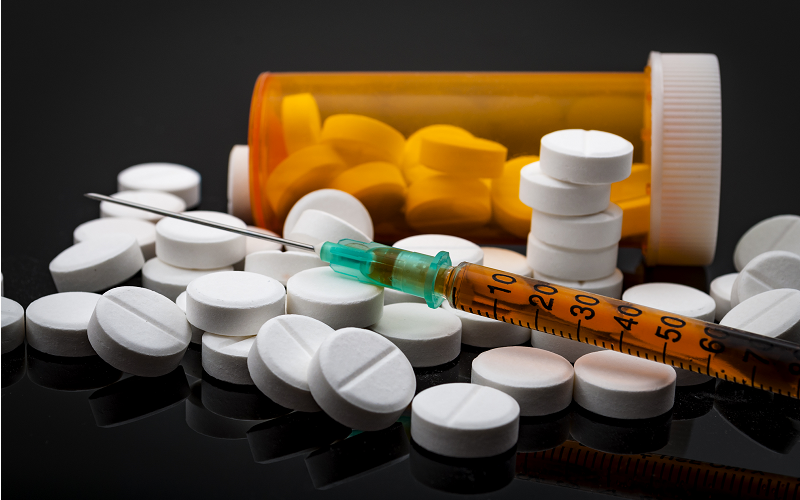 Syringe with glass vials and medications pills drug on white