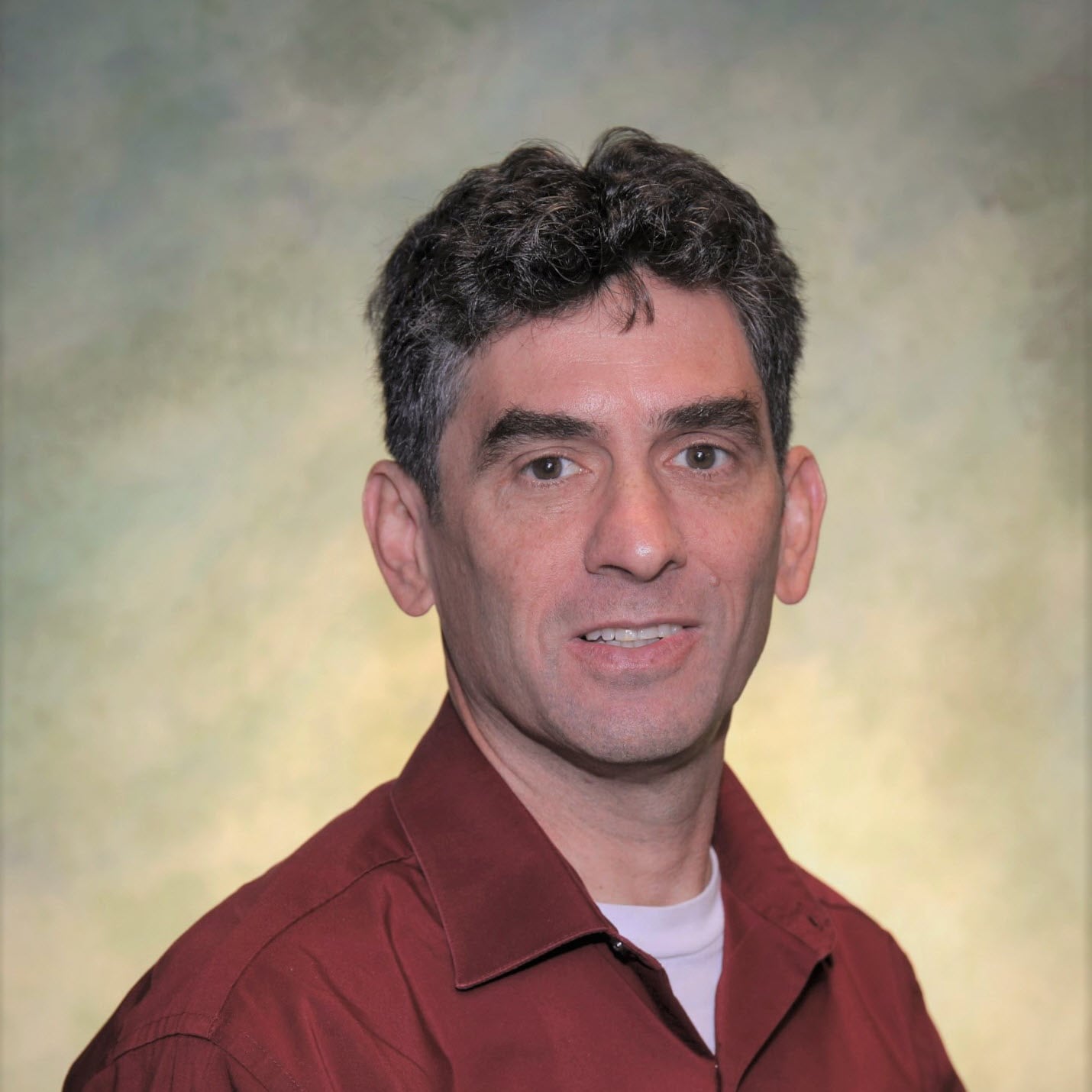 A smiling man wearing red buttoned shirt.