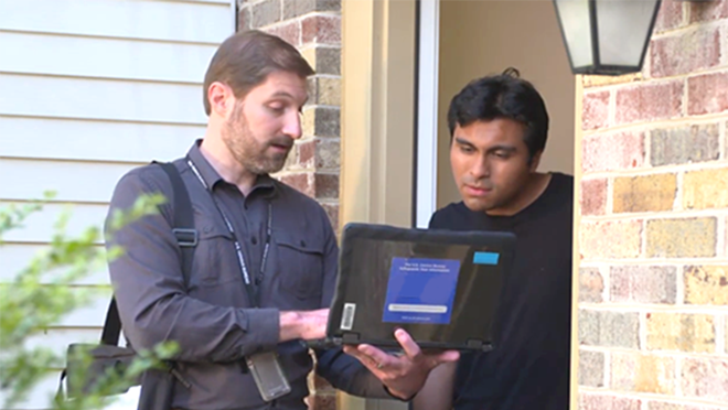 Man standing with laptop and interviewing her at her front door