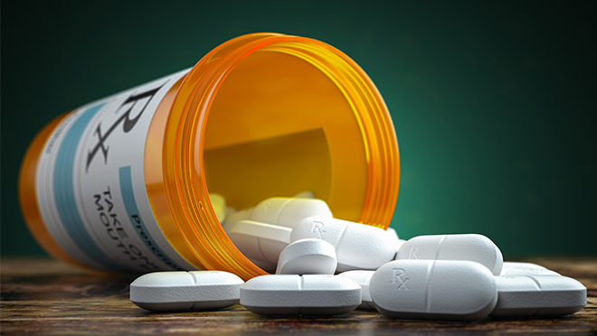 Prescription pill bottle, overturned and spilling pills