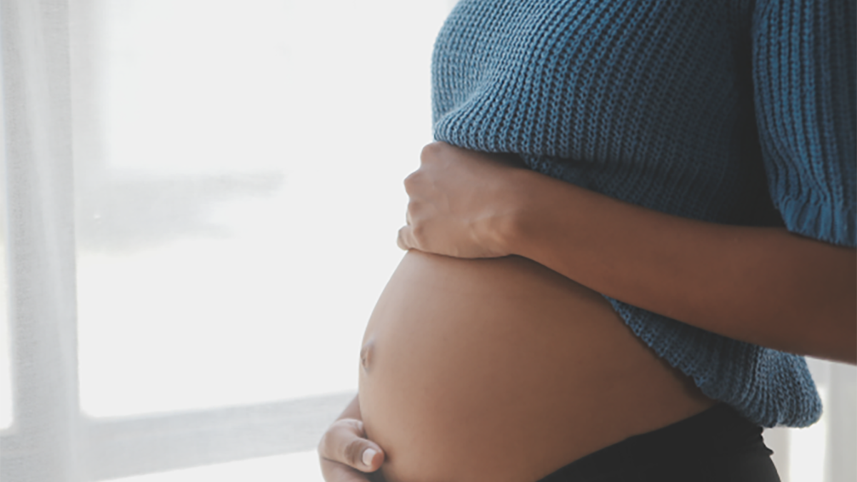 A pregnant woman with hands on her abdomen