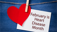 Red heart and card saying "February is Heart Month" held by a clothespin on a string over a blue background