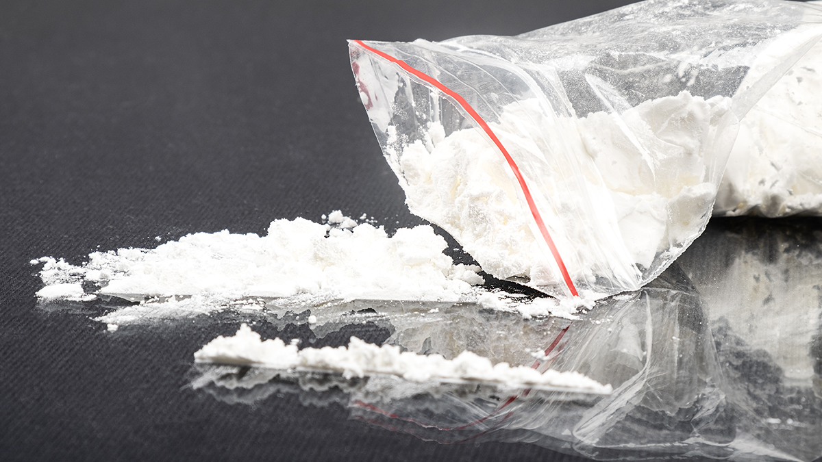Cocaine spills out of a baggy onto a grey surface