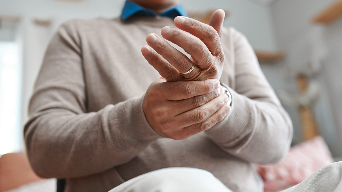 Man sits on bed holding wrist as if it hurts