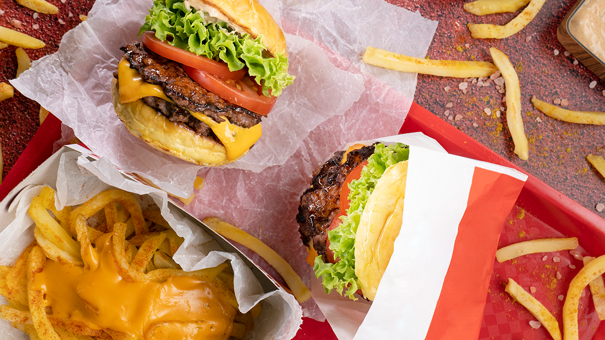 Burgers, cheese fries, and fast food tray scattered on a table