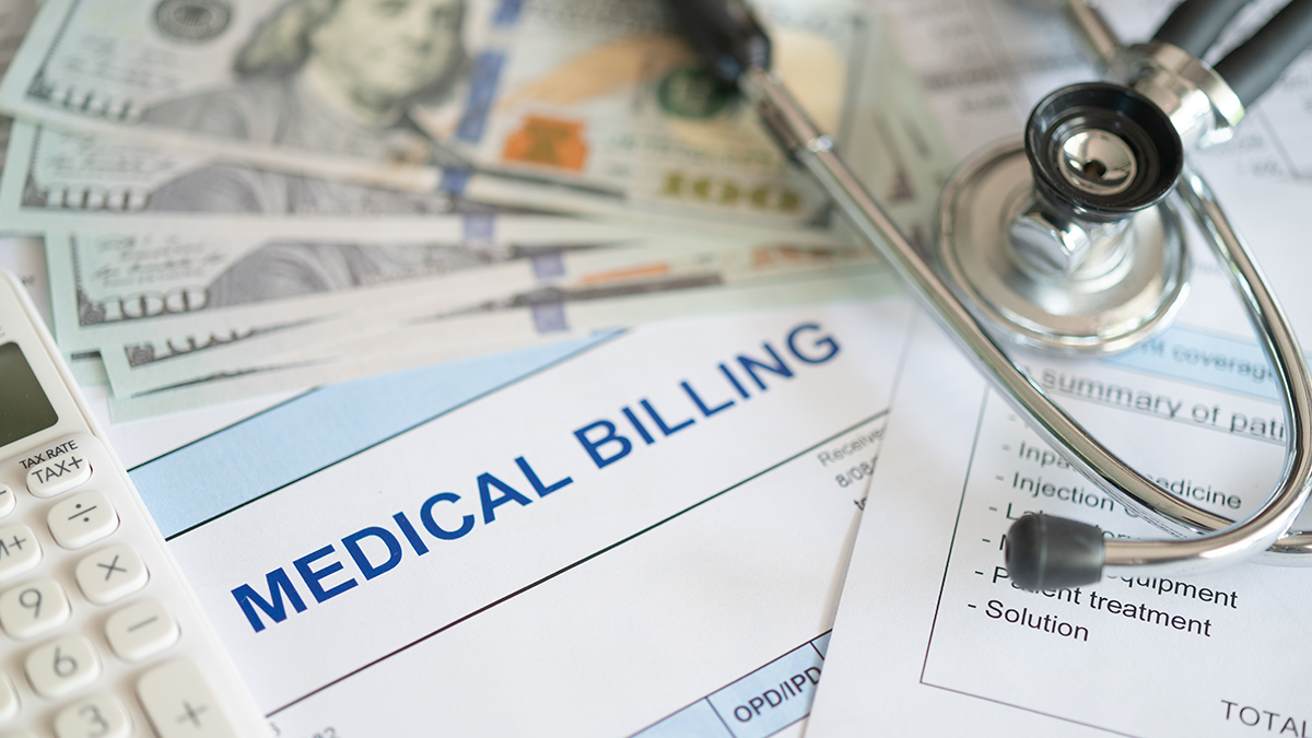 Pile of medical bills, $100 bills, calculator, and stethoscope