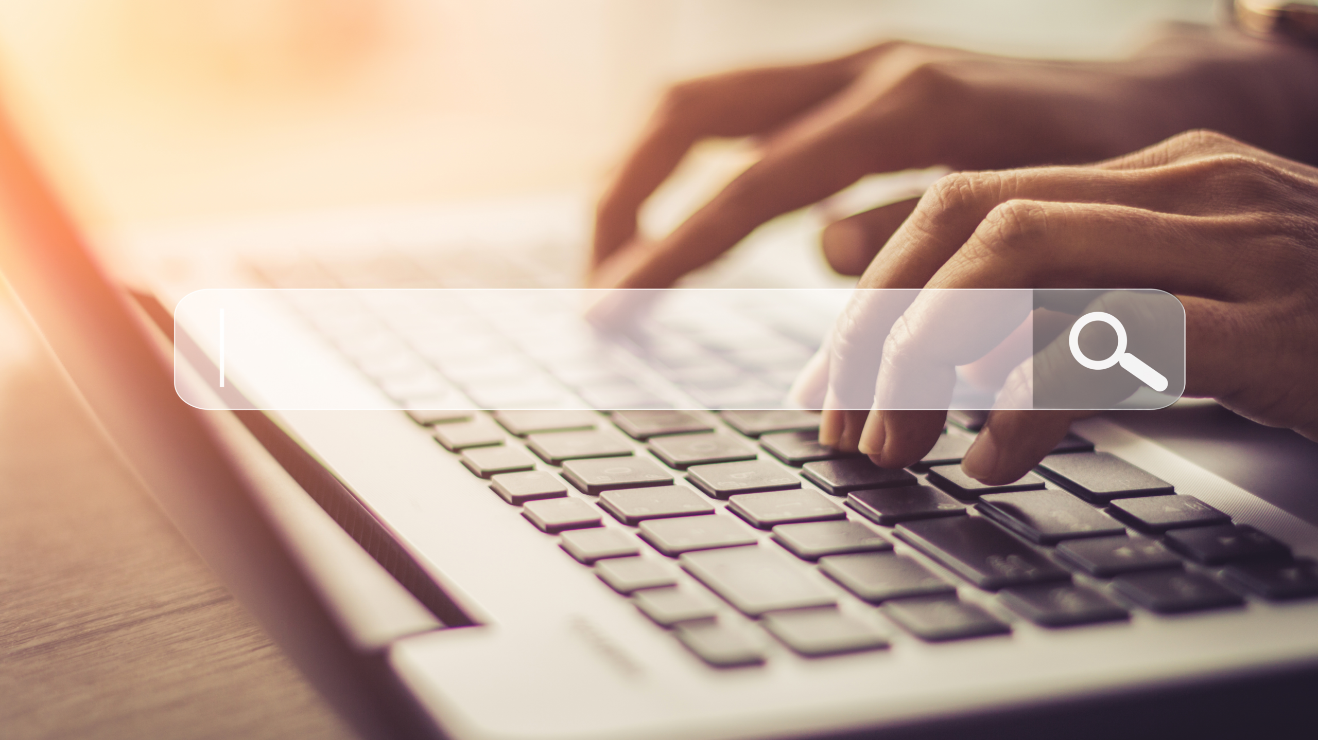Hands type on laptop with search bar superimposed over the image