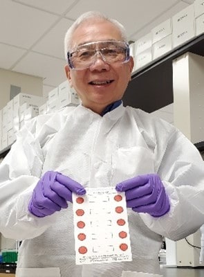 CDC Research Microbiologist Francis Lee holding dried blood spots.