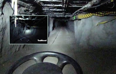 This photo shows a mining tunnel. The ceiling is gridded with what looks like a system of steel pipes and bars. Running along the right side is a yellow tube. The picture is taken from the perspective of a rail car driving down the tracked tunnel%26mdash;as evidenced by the top third of a steering wheel at the bottom center of the picture. Inset is another picture (labeled before) of the same scene. Most of the ceiling and walls are in complete darkness. One bright spot of light illuminates a small part of the tunnel directly in from of the rail car.