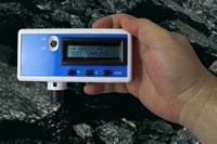 Photo of a Coal Dust Explosibilty Meter (CDEM). Held within a person%26rsquo;s hand and in a mine, demonstrating the real-time operability of the CDEM. The CDEM is indicating Green, Test Complete.