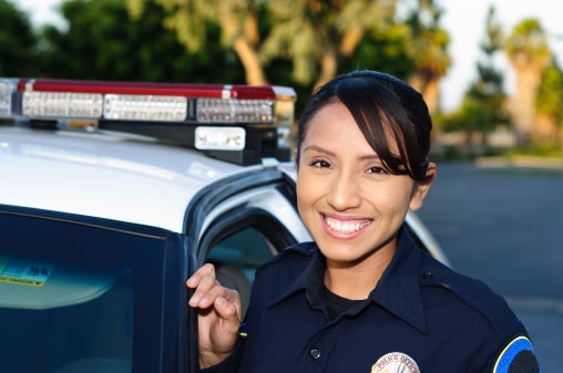 a Hispanic police officer smiling next to her unit