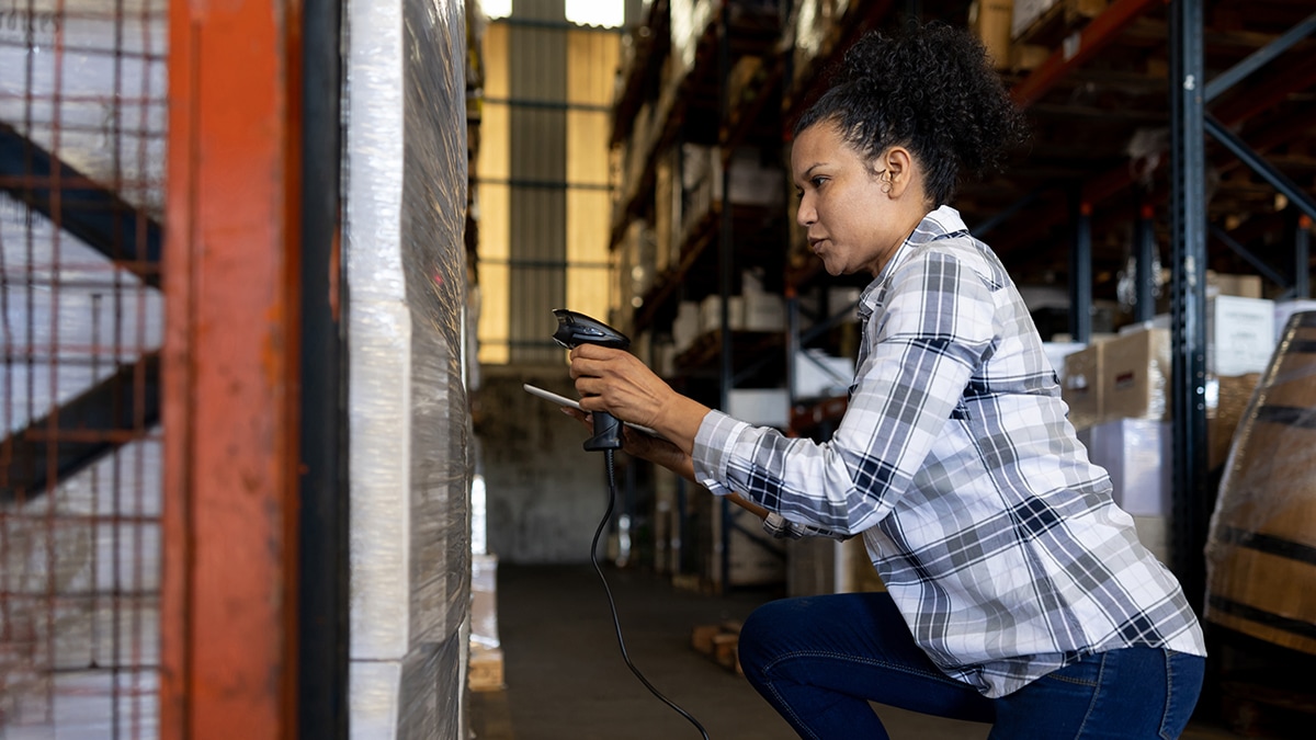 Black woman in plaid shirt working in a factory.