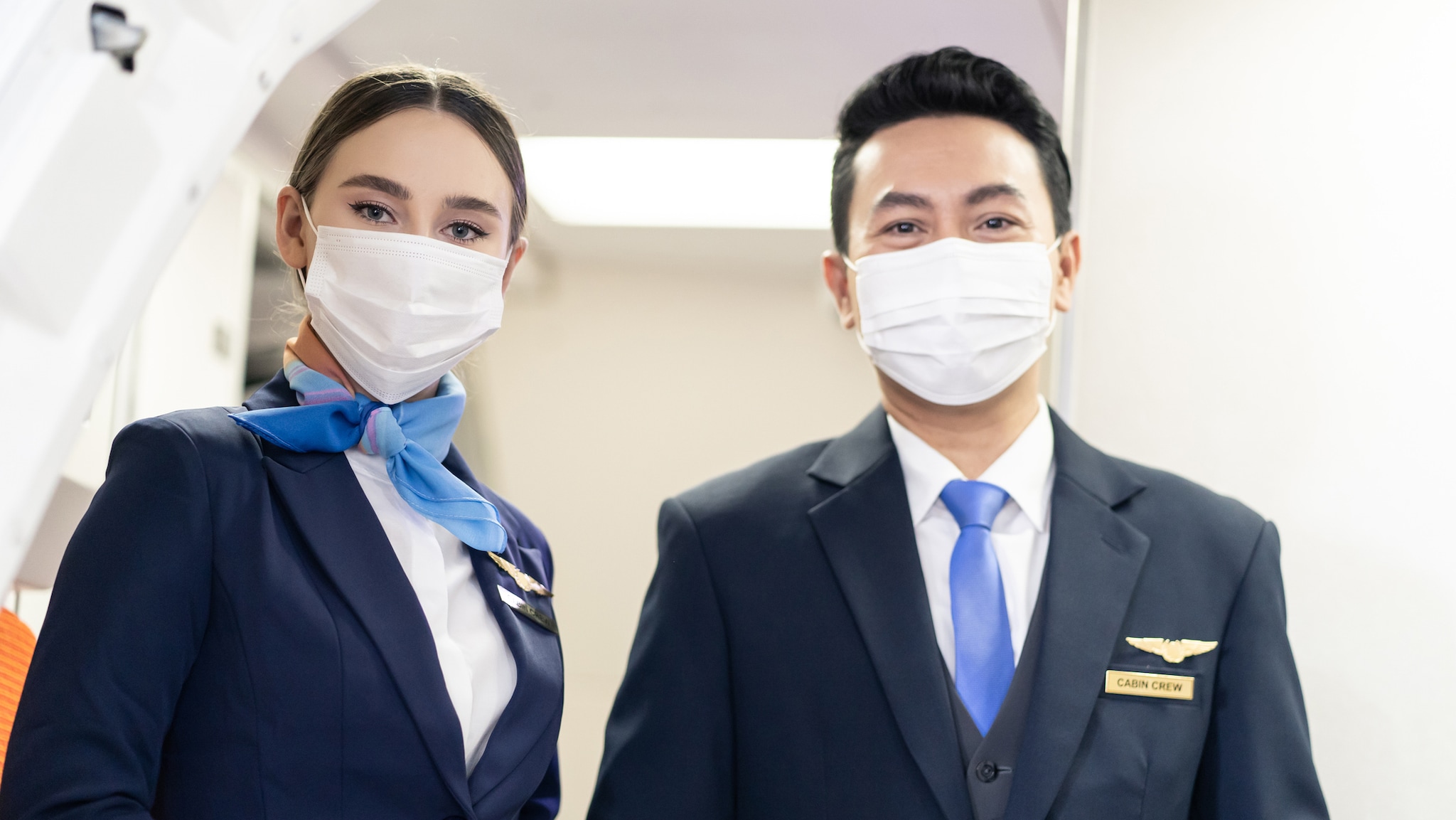 Aircrew members wearing face masks to minimize direct exposure to sick travelers with respiratory symptoms.