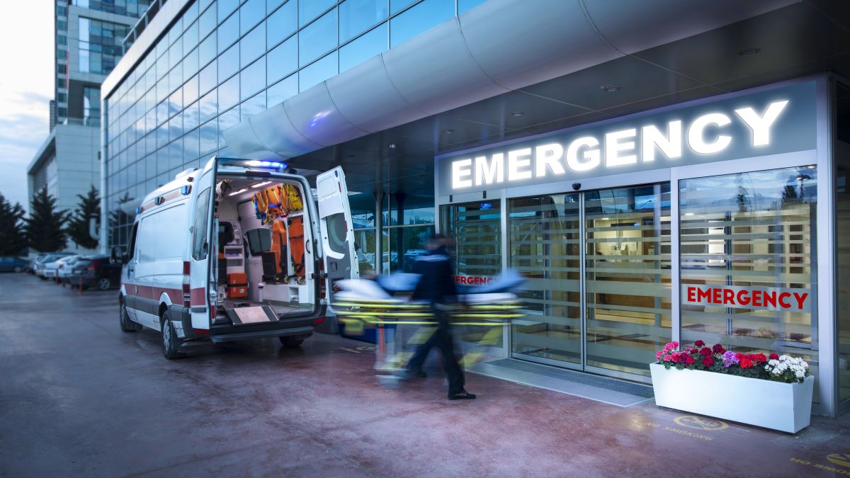 EMTs blurred in motion as they move a patient from an ambulance to the emergency department.