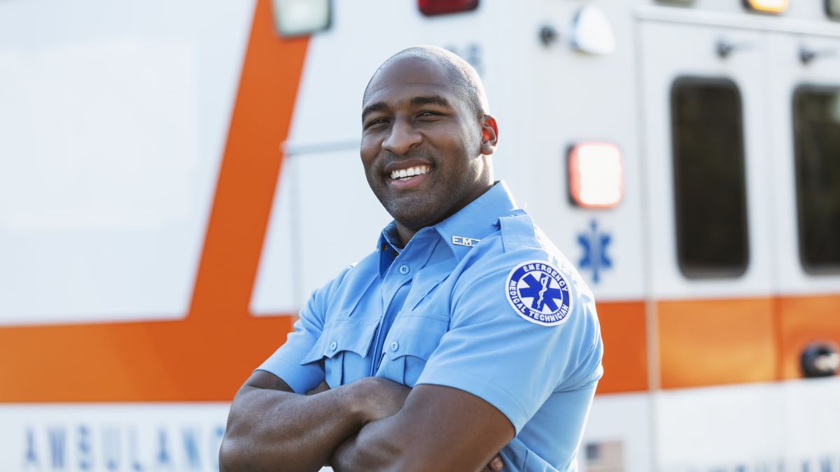 Portrait of an African American male EMT in front of an ambulance.
