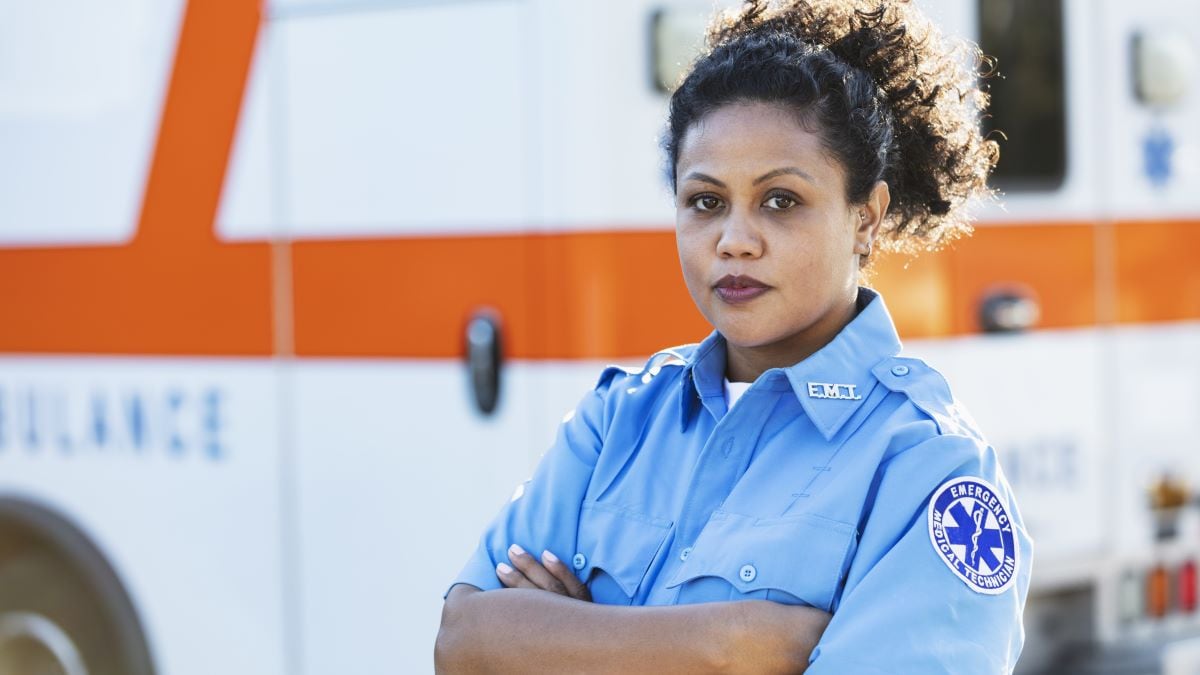Portrait of an Afro-Latina EMT in front of an ambulance.