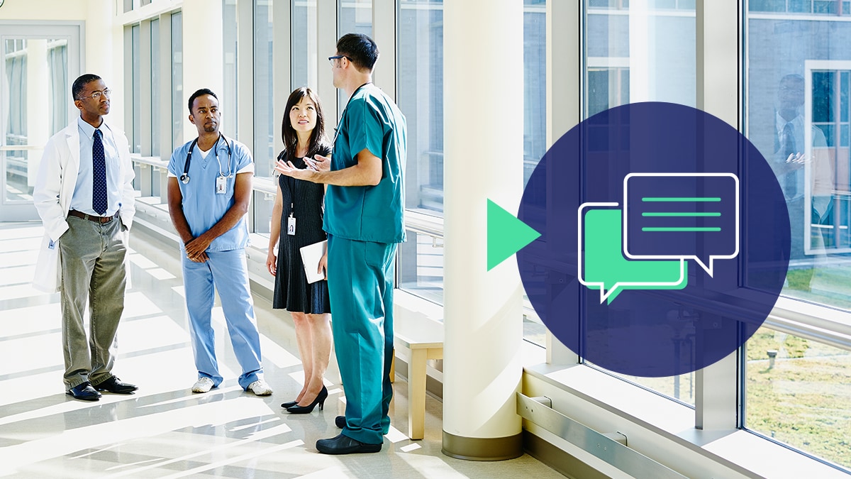 A varied group of healthcare workers chats in a hallway with an icon of overlapping speech bubbles.