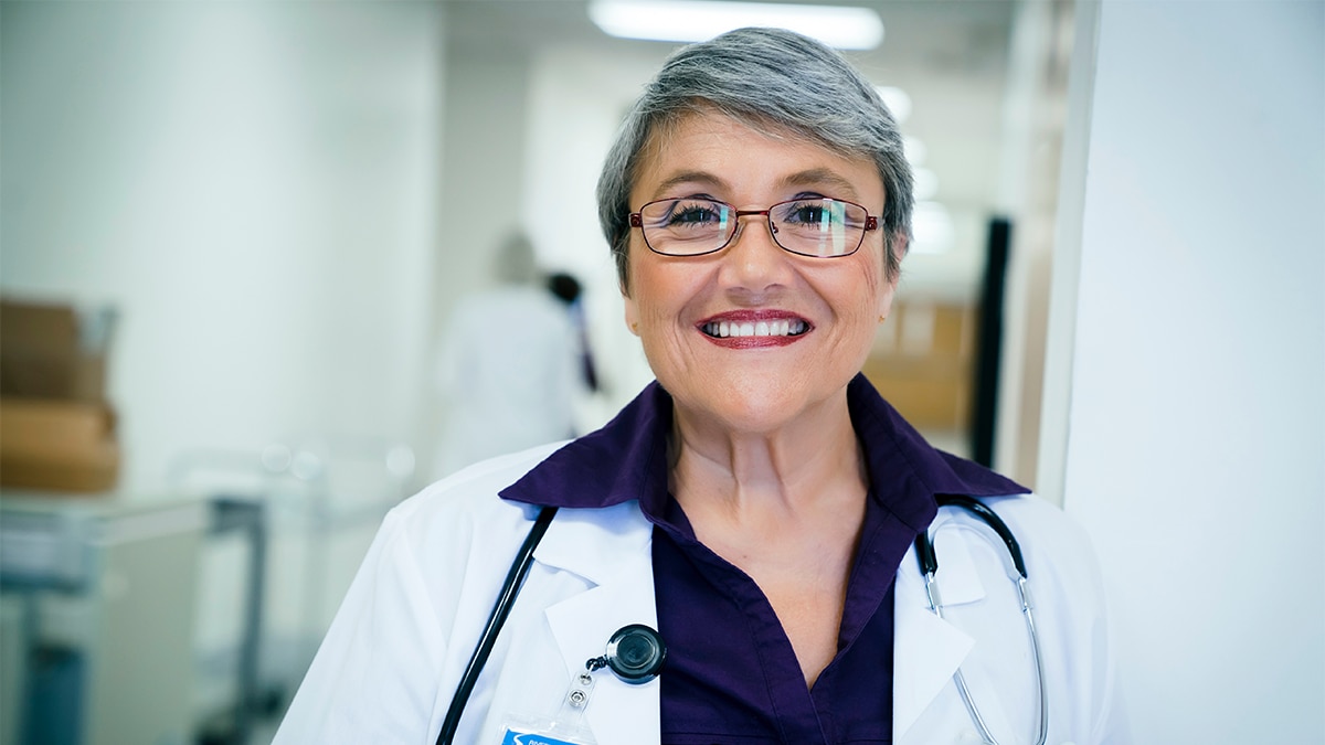 Portrait of an older physician with short graying hair standing in a healthcare facility.