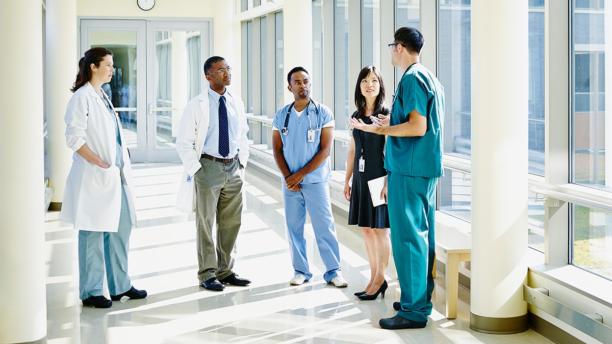 Group of diverse healthcare workers having a conversation in a hospital hallway.