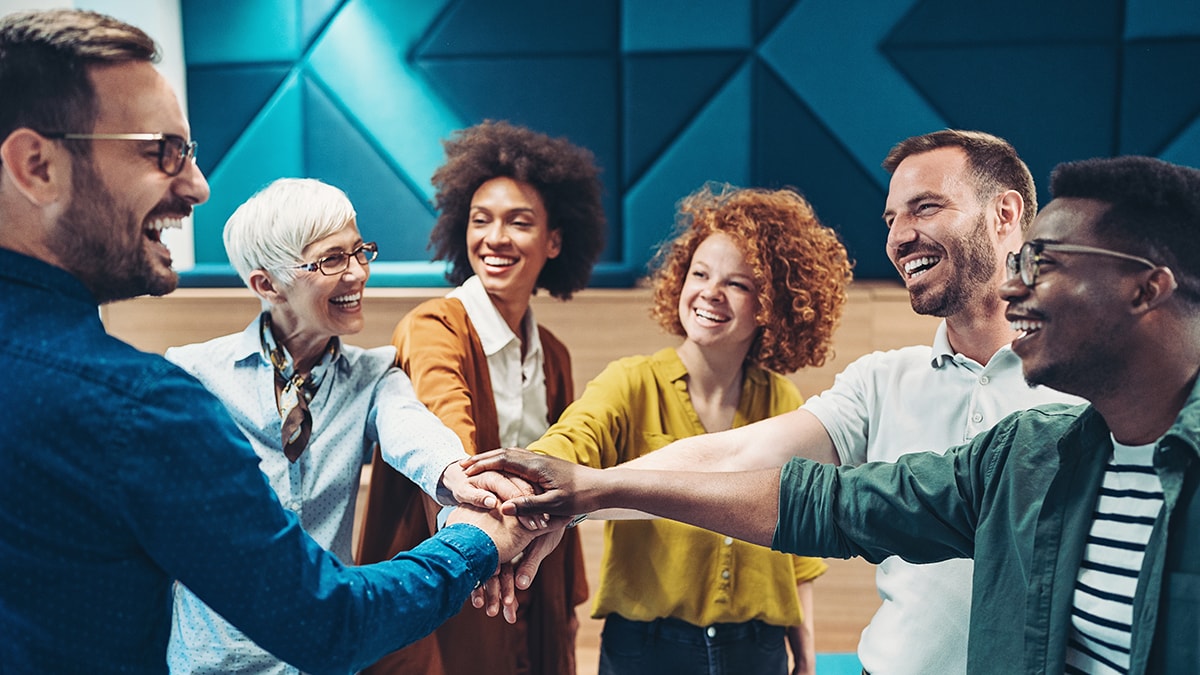 Group of smiling co-workers stacking hands